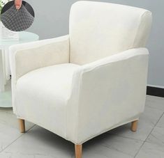 a white chair sitting on top of a tile floor next to a table and vase