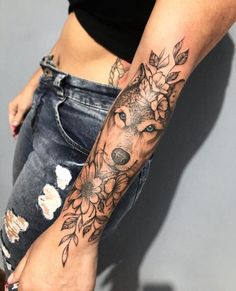 a woman's arm with flowers and a wolf tattoo on the left side of her body