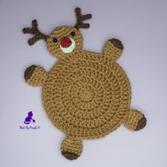 a close up of a crocheted reindeer rug on a white surface with a red nose