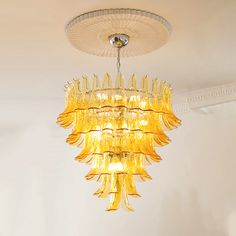 a yellow chandelier hanging from the ceiling in a room with white walls and ceilings