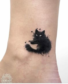 a black cat tattoo on the ankle with ink splatters all over it's body