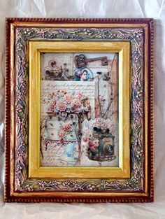 an old fashioned picture frame with flowers and sewing items on the wall above it is covered in tissue paper