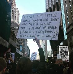 people holding up signs in the middle of a city