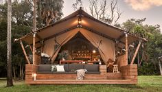 a large tent with couches and lights in the middle of it surrounded by trees