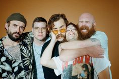 a group of people posing for a photo with one man holding his arms around the other