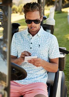 a man sitting in a golf cart looking at his cell phone and writing on paper