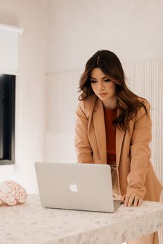 a woman sitting at a table with a laptop computer in front of her, looking down