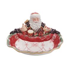 a santa claus figurine sitting on top of a red and white bowl with gold trim