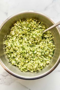 a metal bowl filled with green food on top of a white counter