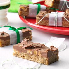 some pieces of food are sitting on a red plate and green ribbon is tied around the edge