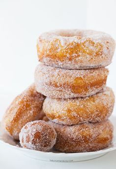 a stack of doughnuts sitting on top of a white plate with powdered sugar