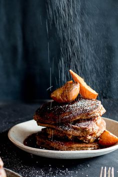 a stack of pancakes on a plate with syrup being poured over them and carrots to the side