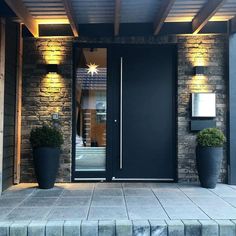 an entrance to a building with two large planters on the steps and one door open