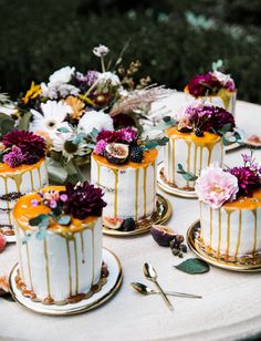 four cakes with flowers on them sitting on top of a table next to each other