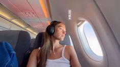 a woman wearing headphones sitting on an airplane