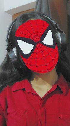 a woman wearing headphones with a spiderman mask on her face