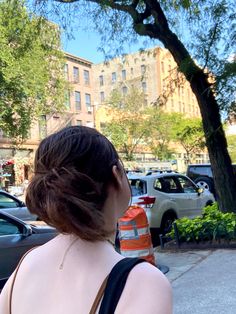 a woman standing in front of a parking meter on the side of a city street