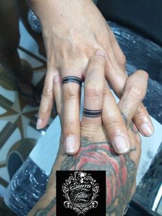 two people holding hands with tattoos on their fingers