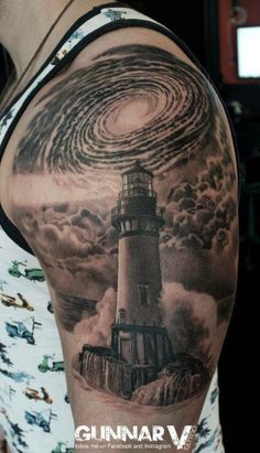 a man with a lighthouse tattoo on his arm and shoulder is looking at the sky