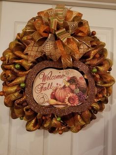 a welcome fall wreath hanging on the front door with autumn decorations and ribbons around it