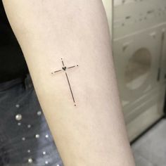 a small cross tattoo on the arm