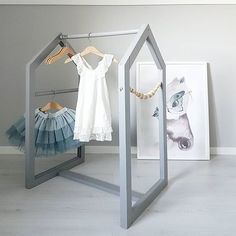 two dresses hanging on clothes racks in a room