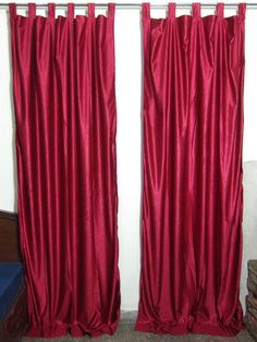 two red curtains hanging on the side of a wall