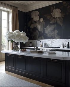 a large kitchen with marble counter tops and black painted walls, along with white flowers in vases