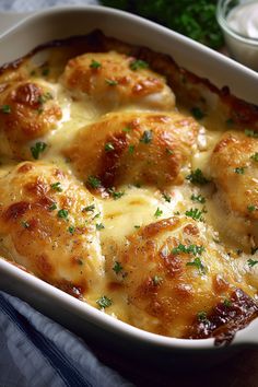 a casserole dish with chicken and cheese in it on a blue table cloth