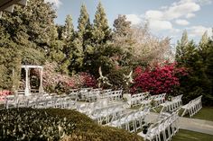 an outdoor ceremony setup with white chairs and flowers