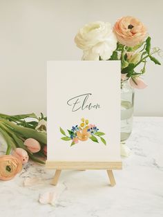 an easel with flowers on it sitting next to a sign that says eleon