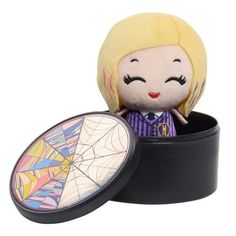 a small doll in a black box with a spider web design on it's face