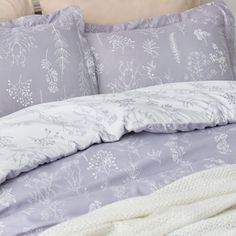 a bed with purple comforter and pillows on it