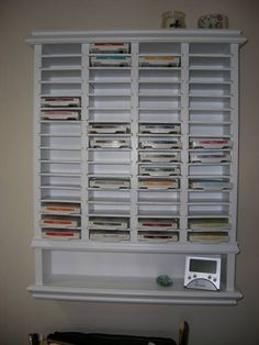 a white book shelf filled with lots of books next to a wall mounted electronic device