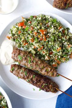 meat skewers with vegetables and yogurt on a white plate