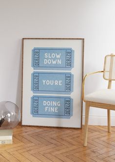 a framed movie poster sitting on top of a hard wood floor next to a chair