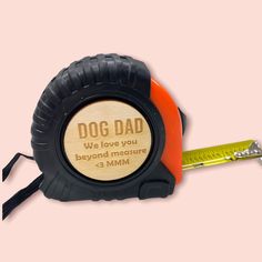 an orange and black measuring tape with a dog dad engraved on it's side