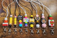 several different colored beads and key chains on a wooden table with white cords attached to them