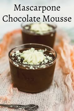 chocolate mousse with whipped cream on top in small glass dishes next to a spoon