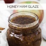 a jar of honey ham glaze sitting on top of a table next to an apple