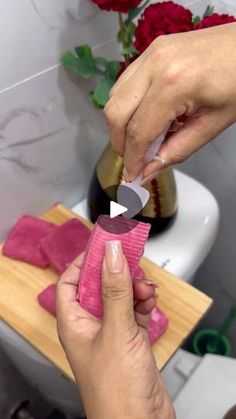 a person is using a knife to cut pink tissue paper