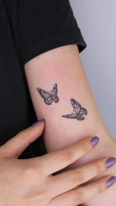 a woman's arm with two small butterflies on the left side of her arm