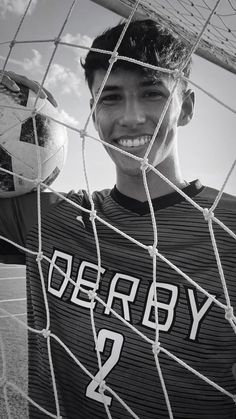 a young man holding a soccer ball in front of a net