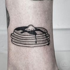 a black and white image of a stack of pancakes with syrup on the side of his leg