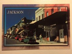 an old photo hanging on the wall in front of a building with cars parked outside