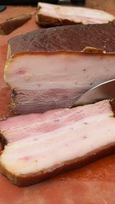 a knife cutting meat on top of a wooden cutting board