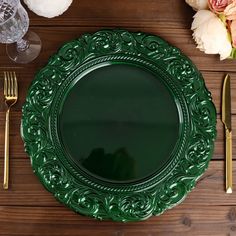 a green plate sitting on top of a wooden table next to gold utensils