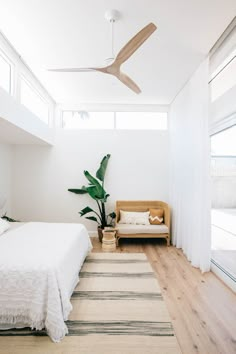 a bedroom with white walls, wooden floors and a ceiling fan that is mounted above the bed