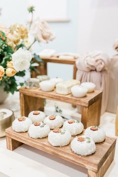 there are many small pastries on the wooden trays with flowers in the background