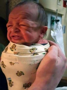 a baby wrapped in a bib is being held up to its face by someone